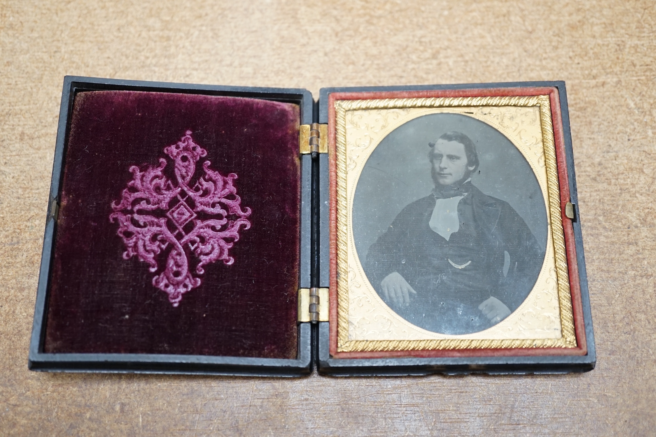 A mid Victorian ambrotype photograph of a gentleman, housed in an original pressed bois durci fireman frame, 9.5cm high. Condition - good